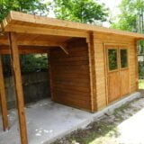 Una pittoresca casetta in legno con tettoia, circondata da alberi e costruita su una base di cemento